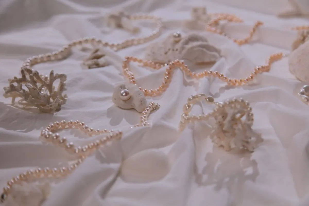 Colliers de perles de culture posés à plat sur un tissu clair