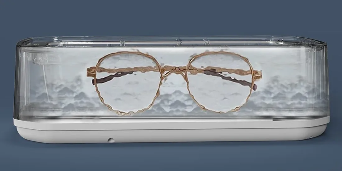 Bagues, montre et paire de lunettes posées près d’un nettoyeur à ultrasons sur un plan de travail